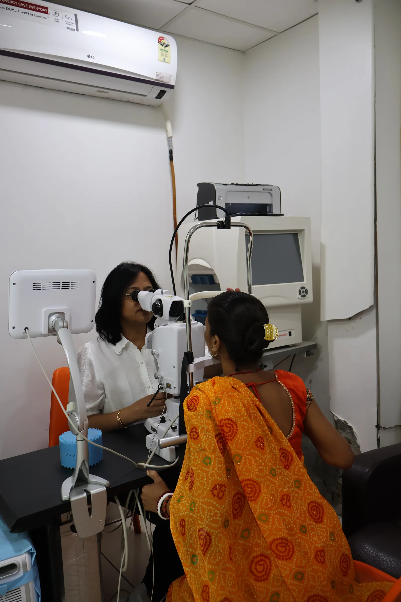 Dr. Poonam Jain examining a patient at a slit-lamp unit; the patient is seen from behind