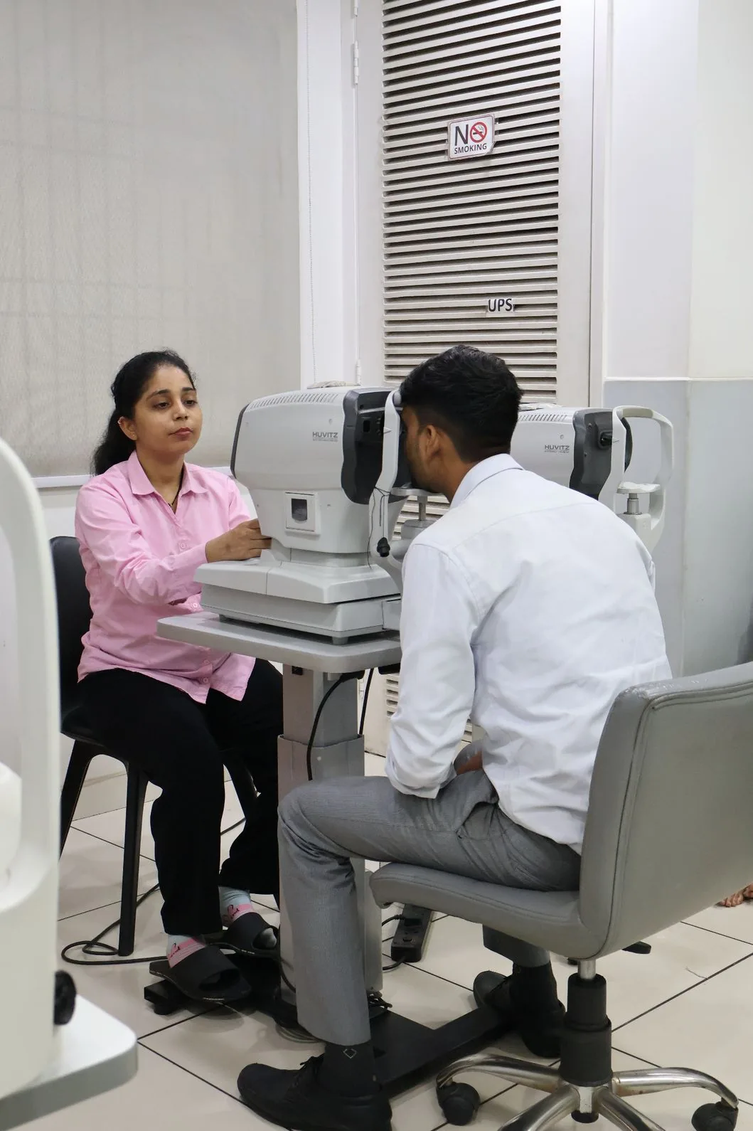 A staff member and a patient at a pre-examination eye-testing instrument
