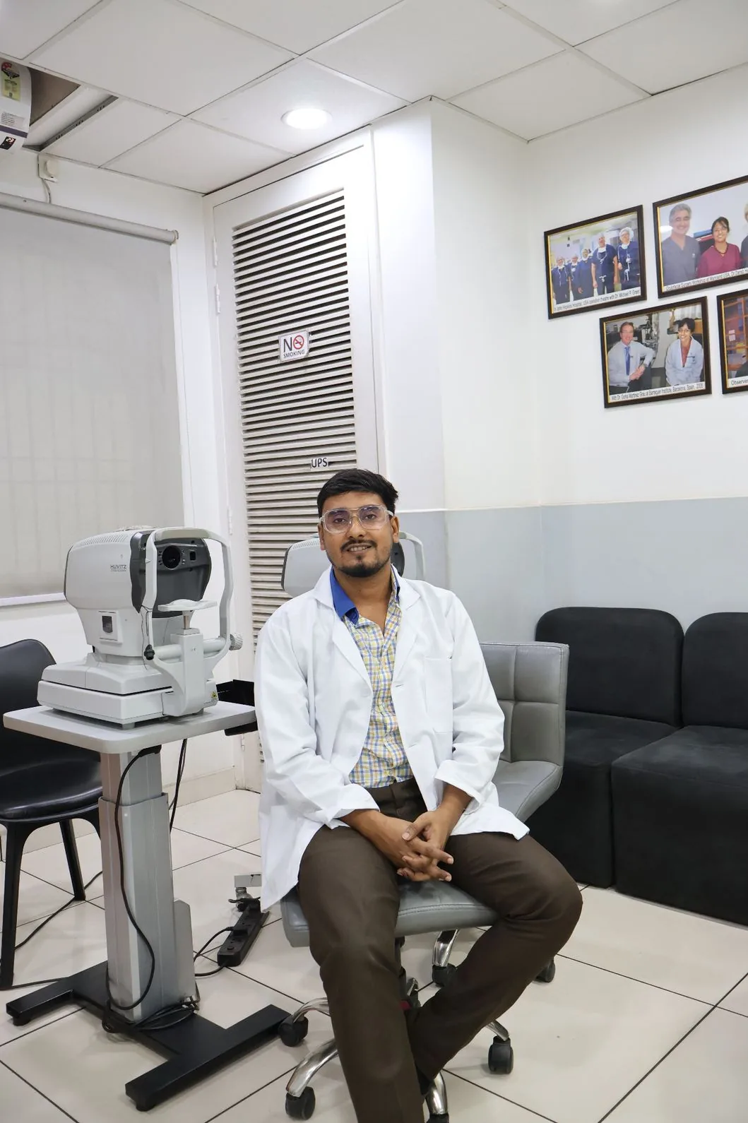 A staff member seated beside an eye-testing instrument in an examination room