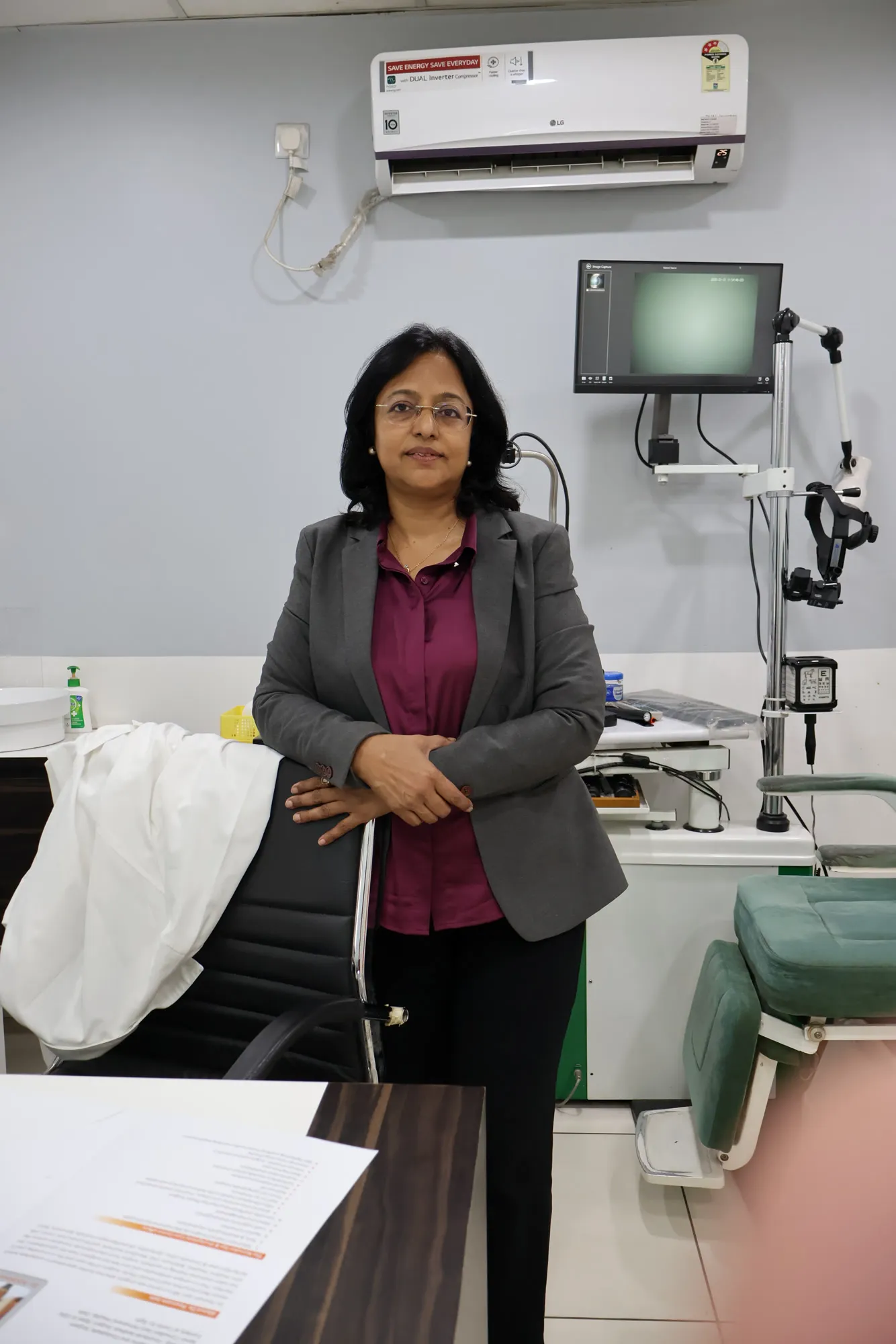 Dr. Poonam Jain in a grey jacket standing in a consultation room